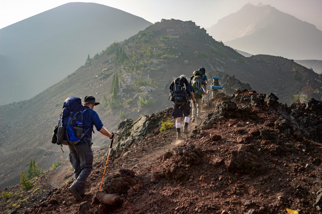 Beyond Safaris Group of hikers trekking on a rugged mountain trail in Oregon's scenic outdoors.