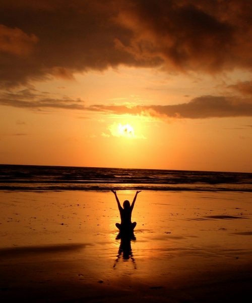 Peaceful meditation silhouette at sunset on a serene beach.